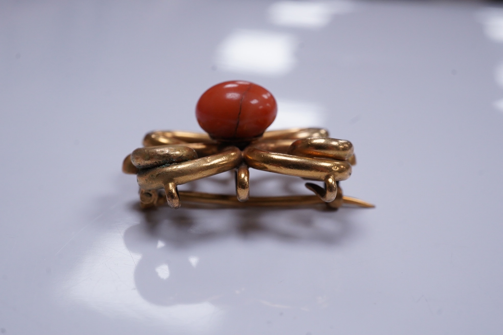 A yellow metal and coral bead set scrolling brooch, 31mm, gross weight 13 grams. Condition - poor